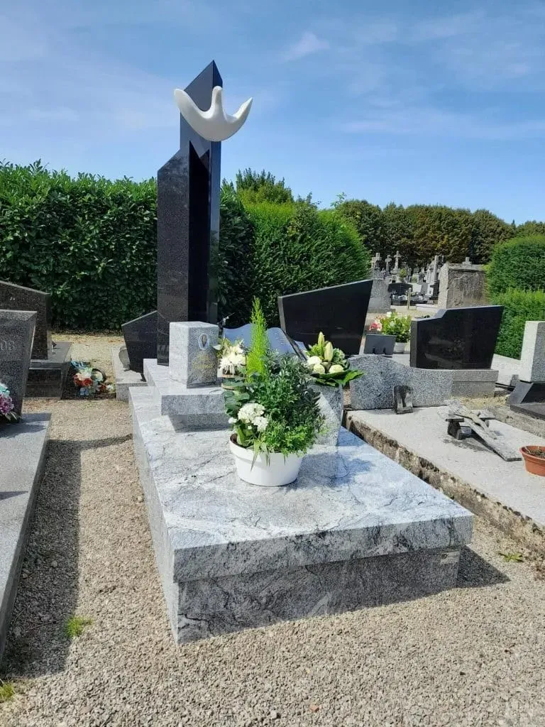 Monument funéraire moderne en granit gris avec stèle ornée d'une colombe.